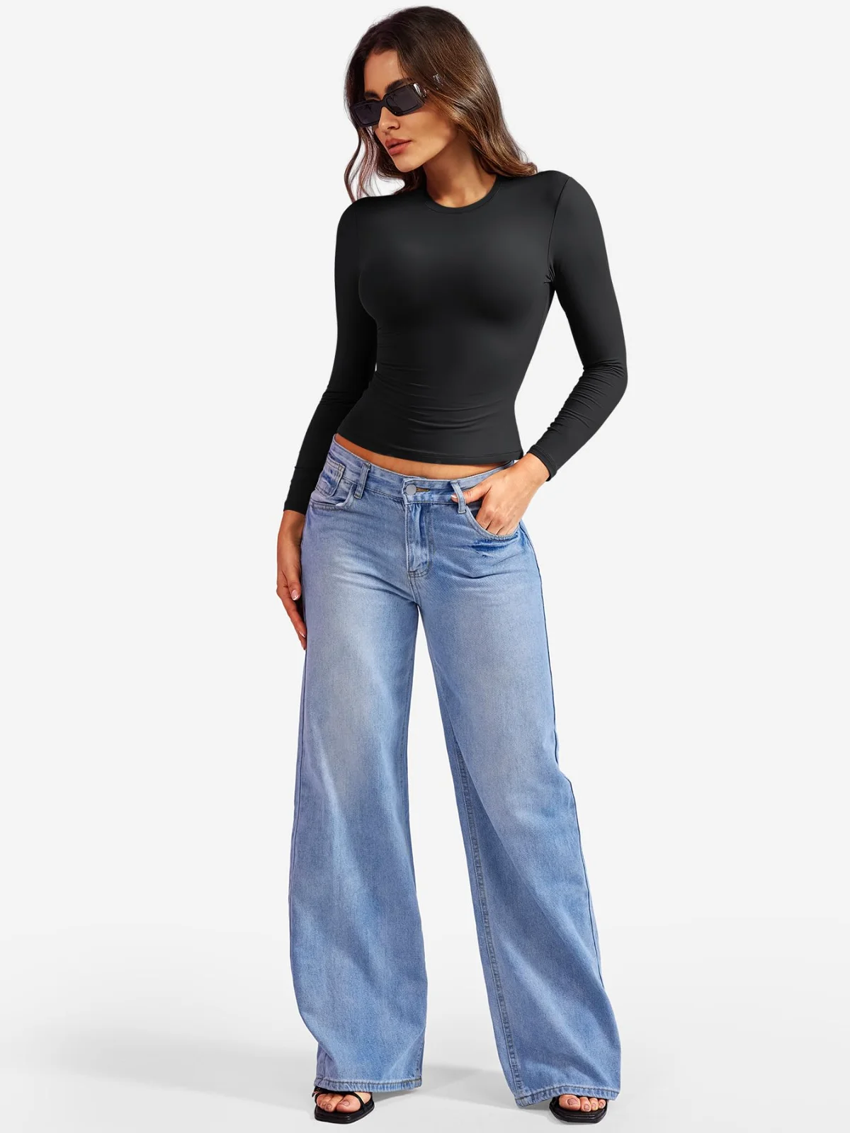A black crew-neck long-sleeve top over light-blue wide-leg jeans, hands in pockets, sunglasses on